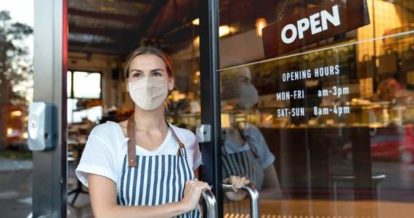 staff member in mask opening restaurant door