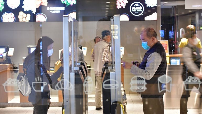 Customers using self-service kiosks to place their orders at a restaurant