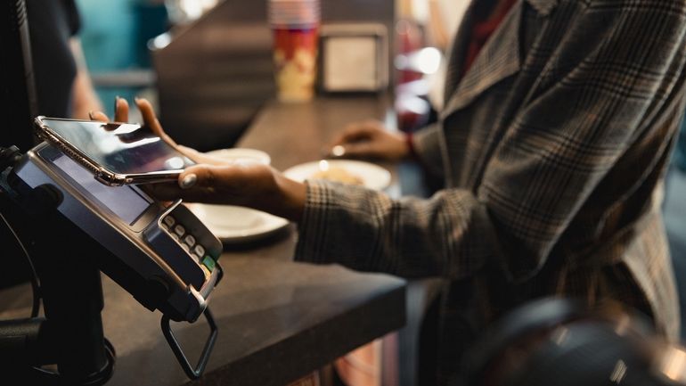 A woman using a mobile phone to make a contactless payment