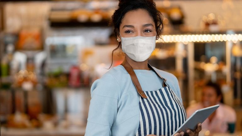 Waitress wearing a mask while holding a tablet