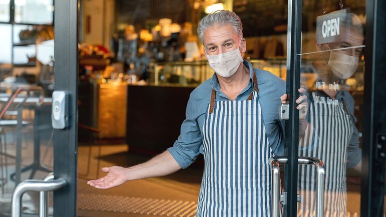 Cafe owner wearing a mask as he reopens his business
