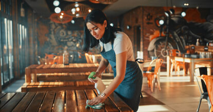 Restaurant staff member wiping down a table.