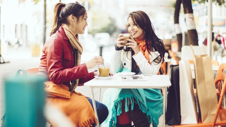 Two women sitting on a cafe patio with blankets
