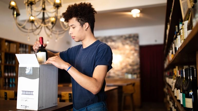 Restaurant worker packing a bottle of wine into a box