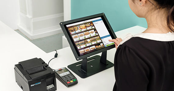 Woman tapping on an iPad to order food from a self-ordering kiosk