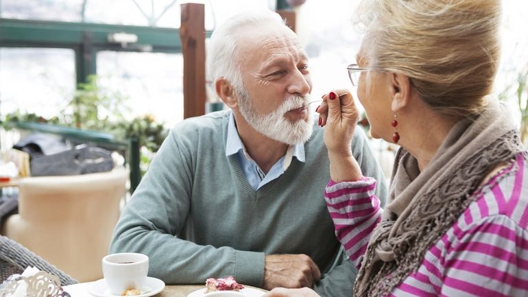 Woman feeding a man a piece of cake at a restaurant