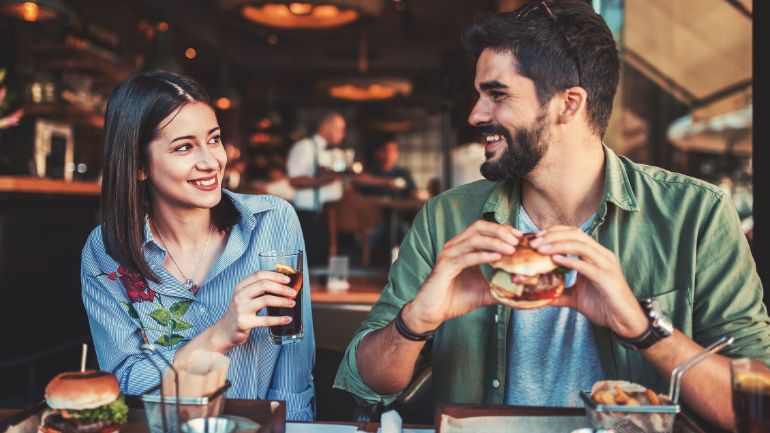 A couple smiling while enjoying burgers 