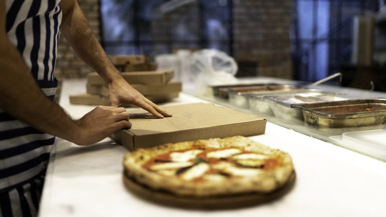 Man preparing a pizza for takeout