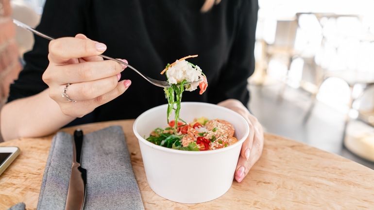 Woman eating a takeout poke bowl