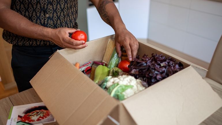 Man unpacking produce from a delivery a meal kit