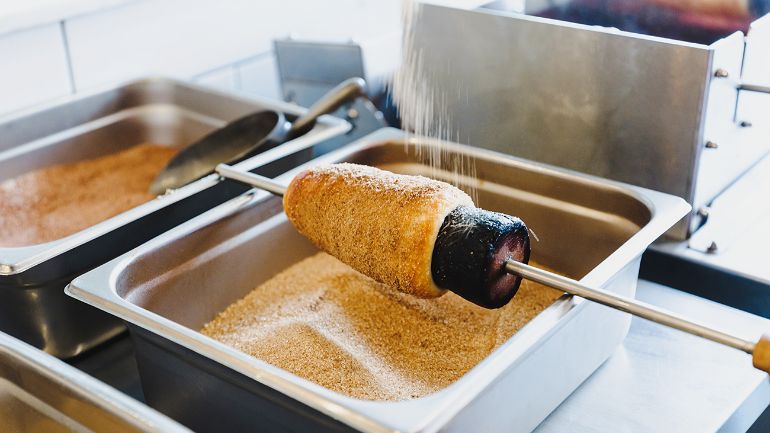 Chimney pastry being sprinkled with topping