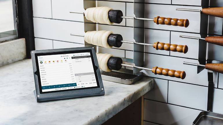 iPad on the prep counter with some chimney pastries hanging off a rack in the background