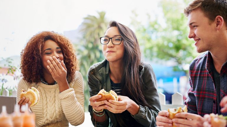Three friends eating burgers together