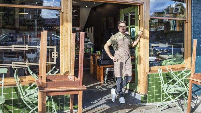 Cafe owner standing in open cafe doorway