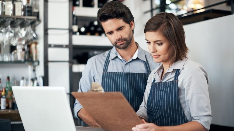 Restaurant workers using a laptop and a clipboard