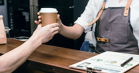 Restaurant employee handing a coffee to a customer over a counter