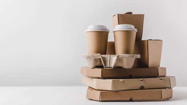 Stack of brown paper takeaway boxes trays cups and packages