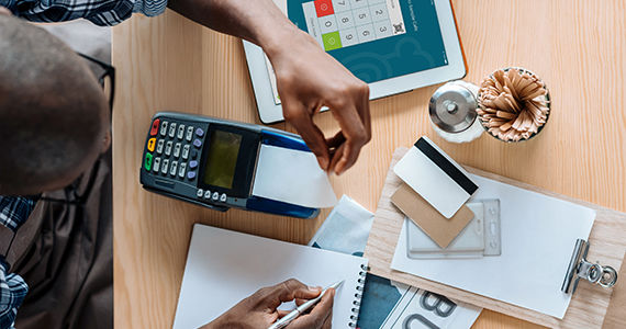 A man sitting at a restaurant table ready to work with payment terminal and TouchBistro iPad software