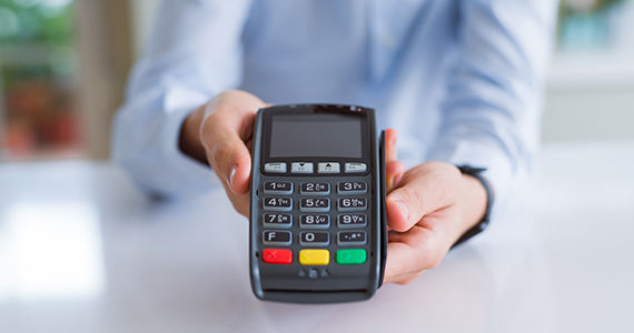 Restaurant employee holding a payment terminal towards you