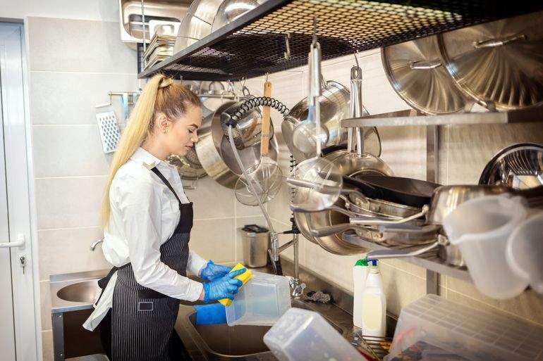 Worker washing containers in a restaurant kitchen
