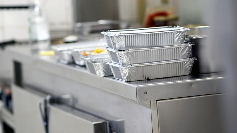 A pile of takeout boxes on a kitchen counter