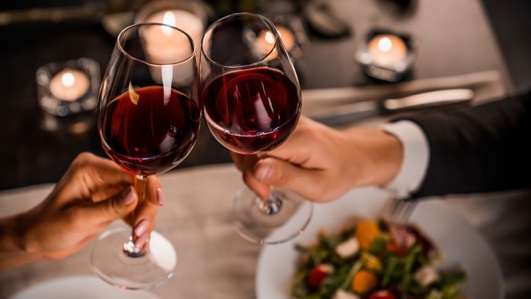 Couple cheersing with glasses of red wine at a restaurant