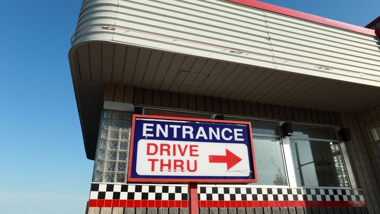 Sign for a drive-thru entrance in front of a retro diner