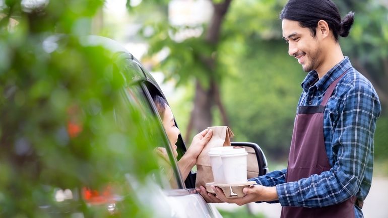 Waiter bringing an order to a customer in her car