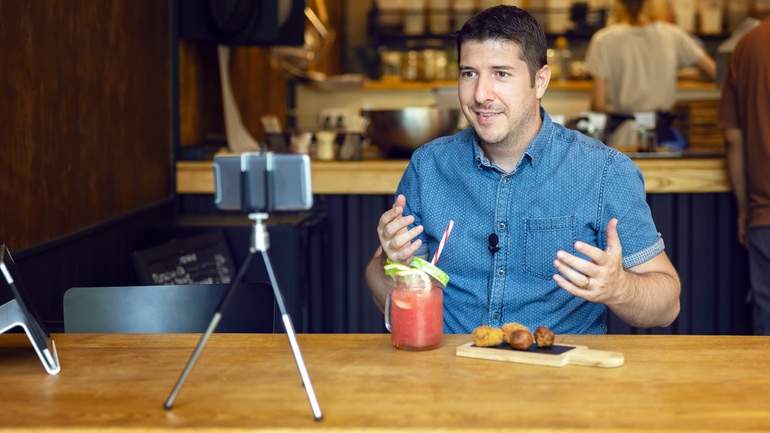 Food blogger filming a video in front of a smartphone on a tripod
