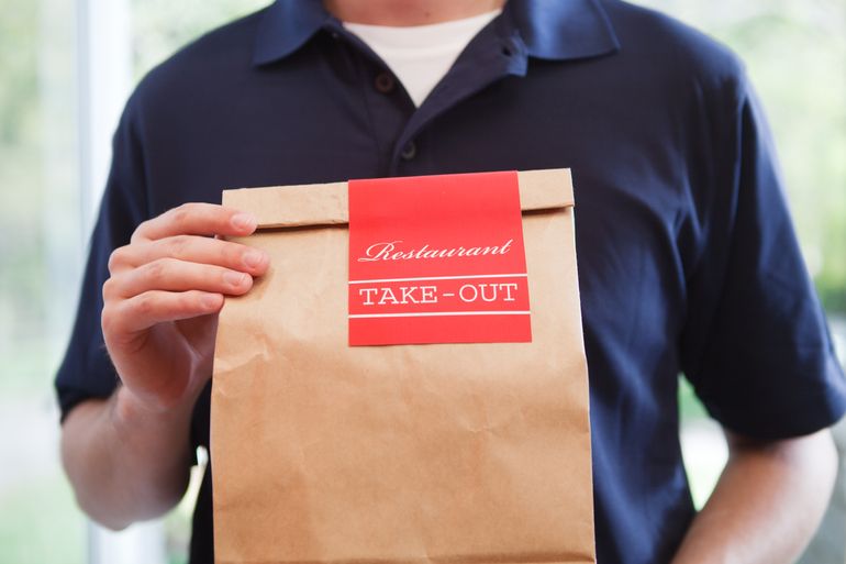 Delivery person with take-out food in paper bag
