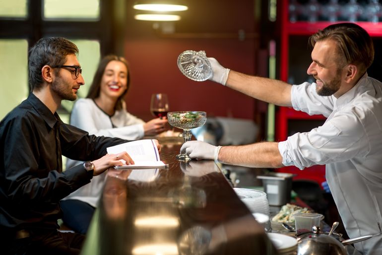 A chef giving a diner a preview of a dish at a soft opening