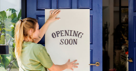 A restaurant employee sticking an opening soon sign on restaurant door