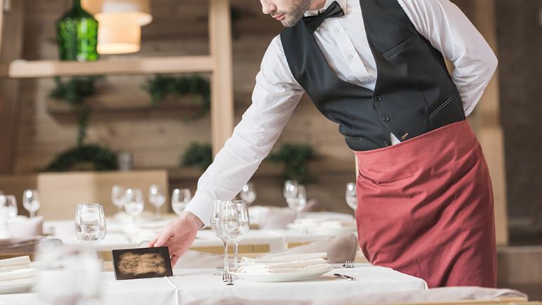 Server placing a card on a set dining table