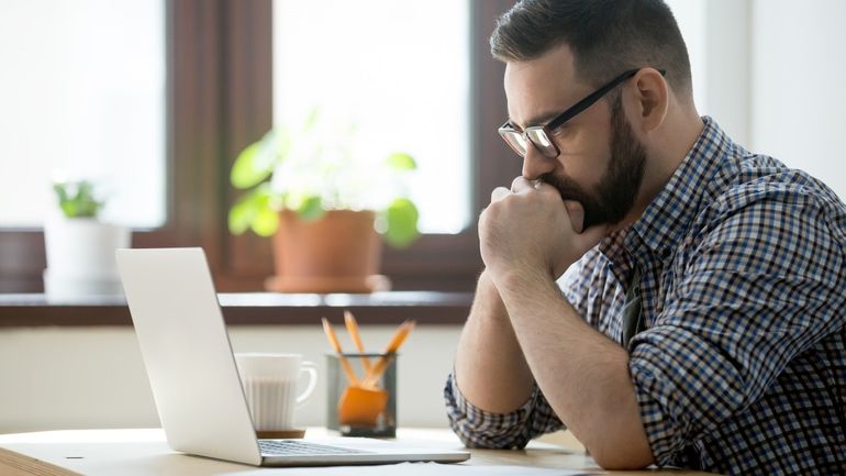 Man thinking and looking at a laptop