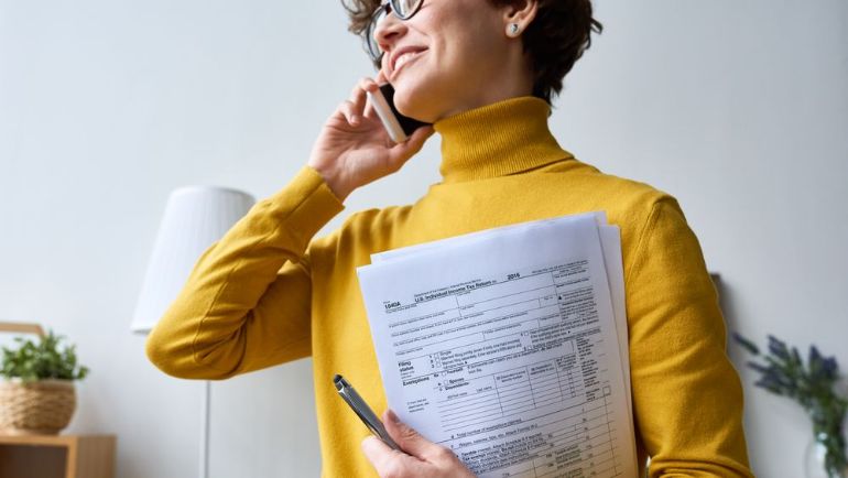Employee with tax forms in hand making a phone call