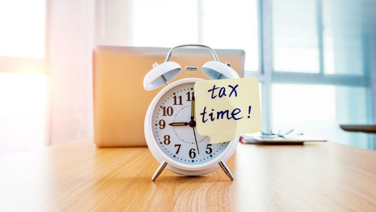 Old fashioned alarm clock with sticky note reminder that it is tax time