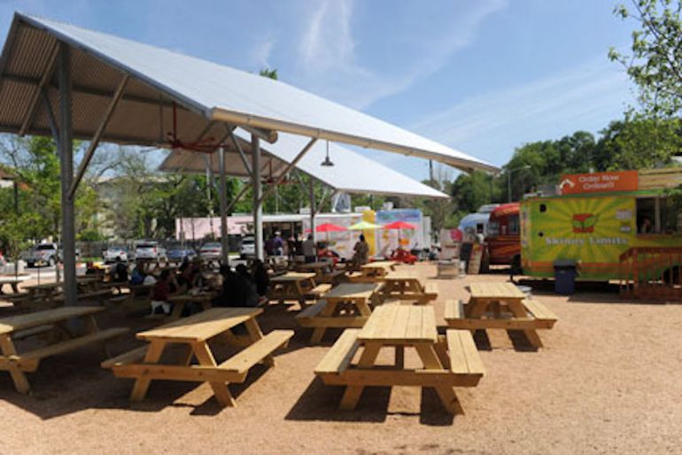 Outdoor picnic benches under some shelter by a food truck