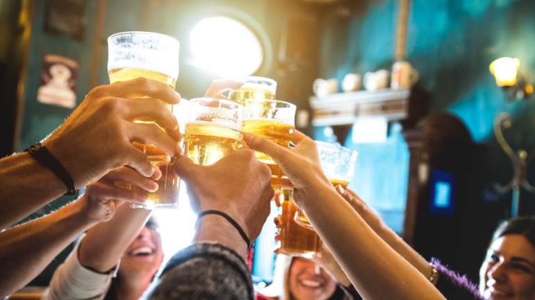 Friends smiling and raising their glasses in a bar.