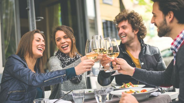 Friends around a table raising their glasses