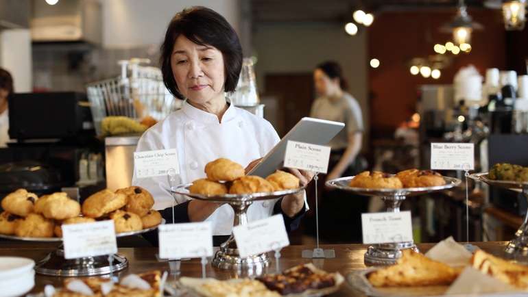 Pastry chef taking inventory of baked goods in counter display