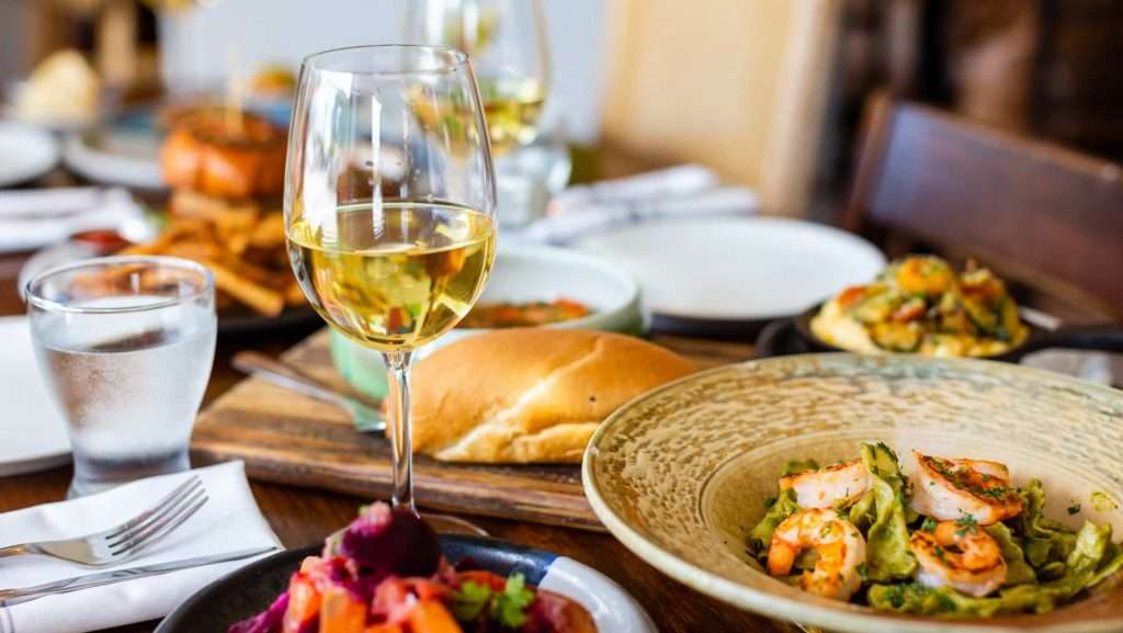 Pasta, wine dish, and bread on a dining room table at Pinch Kitchen, a destination restaurant near Miami