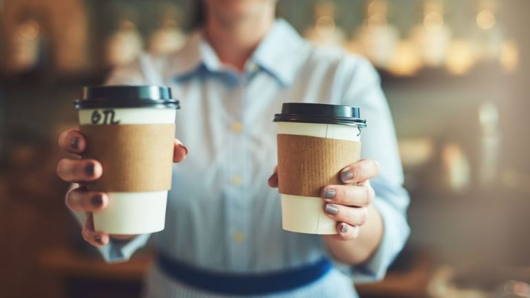 Barista handing over two take away coffees