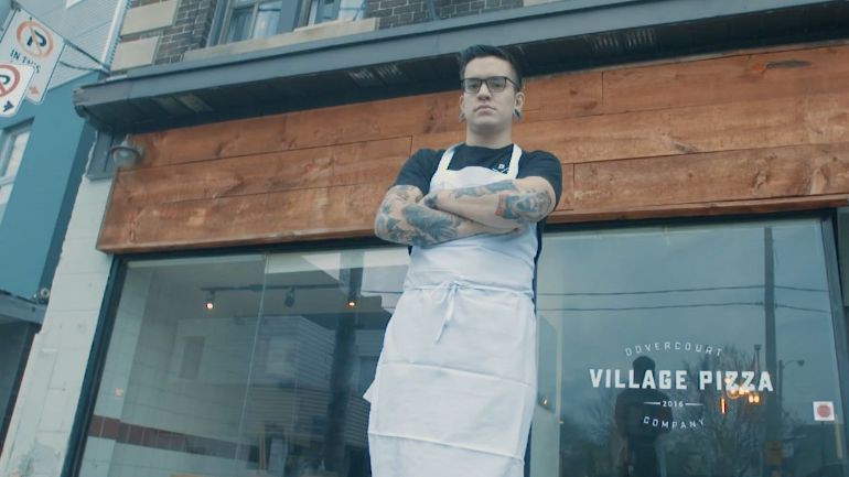restaurateur standing in front of village pizza, ready for the restaurant competition