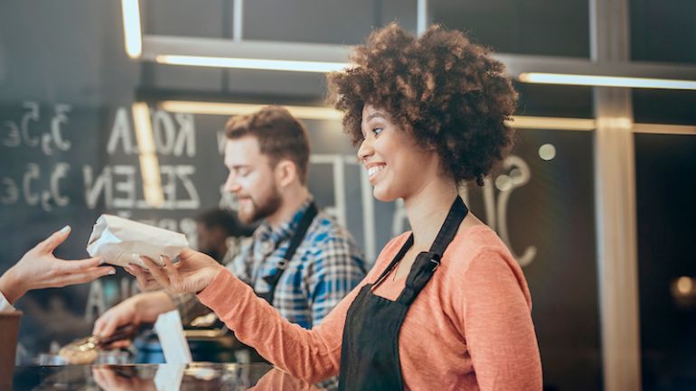 Cafe worker passing customer a wrapped sandwich