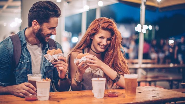 A woman and man enjoying burgers on a restaurant patio