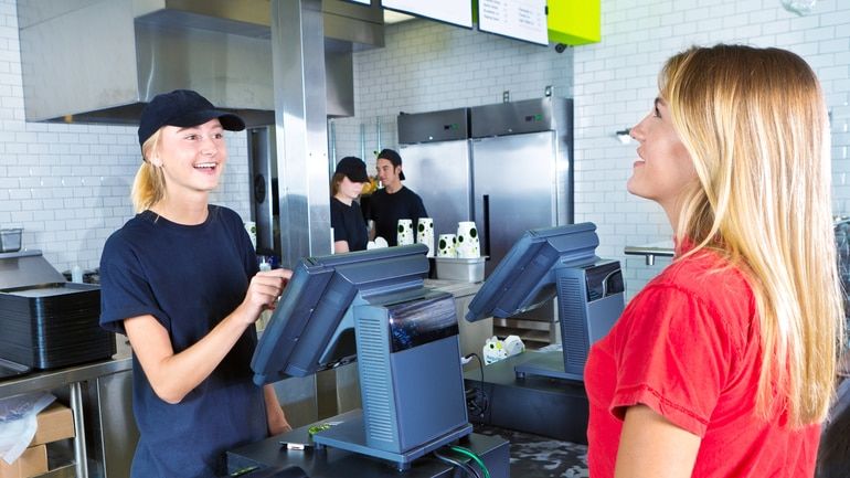 Checkout server serving a woman ordering at fast food restaurant