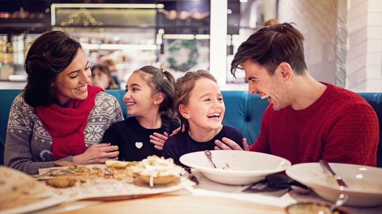 Family of four smiling at a restaurant table