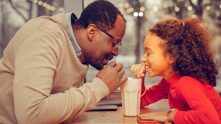 Dad and daughter sharing a milkshake