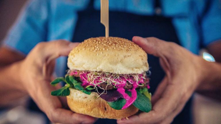 Colourful burger being presented by a chef