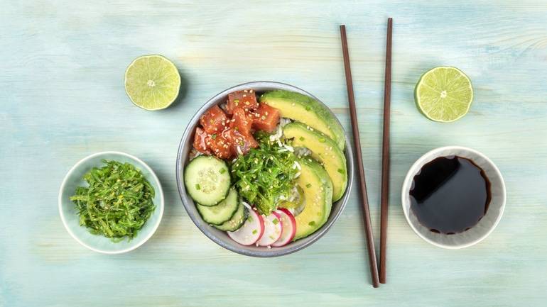 Poke bowl with chopsticks and freshly cut limes